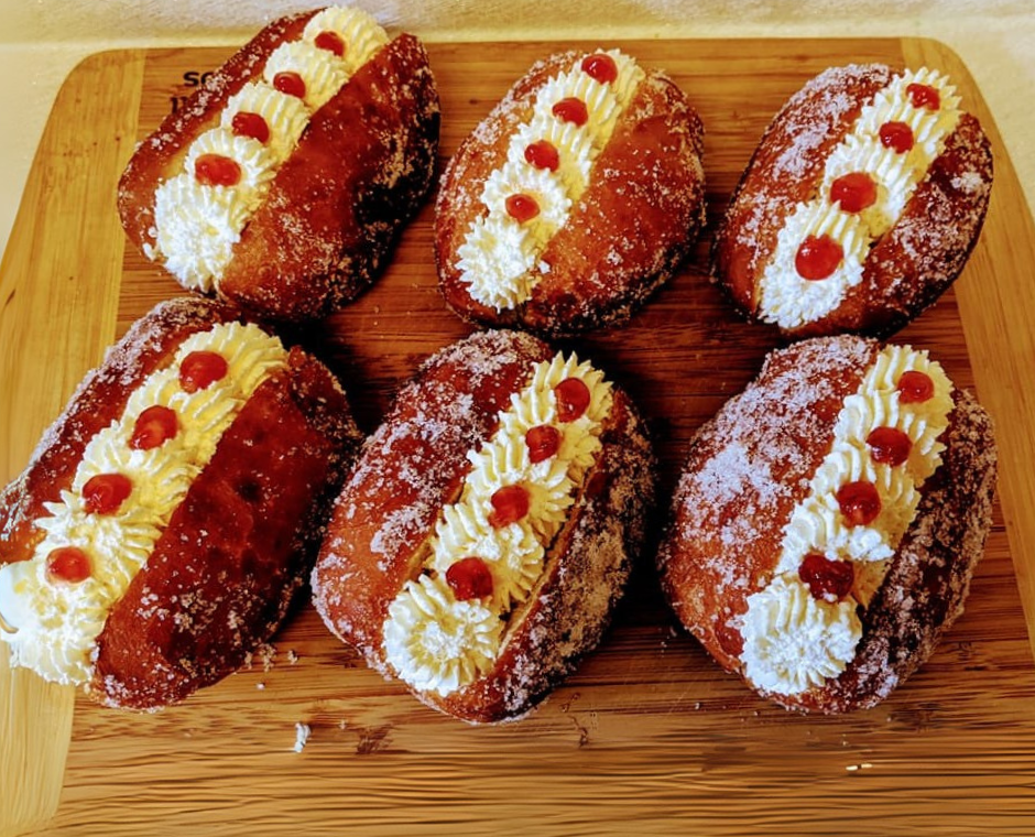 Filled doughnuts with cream and jam on a wooden board